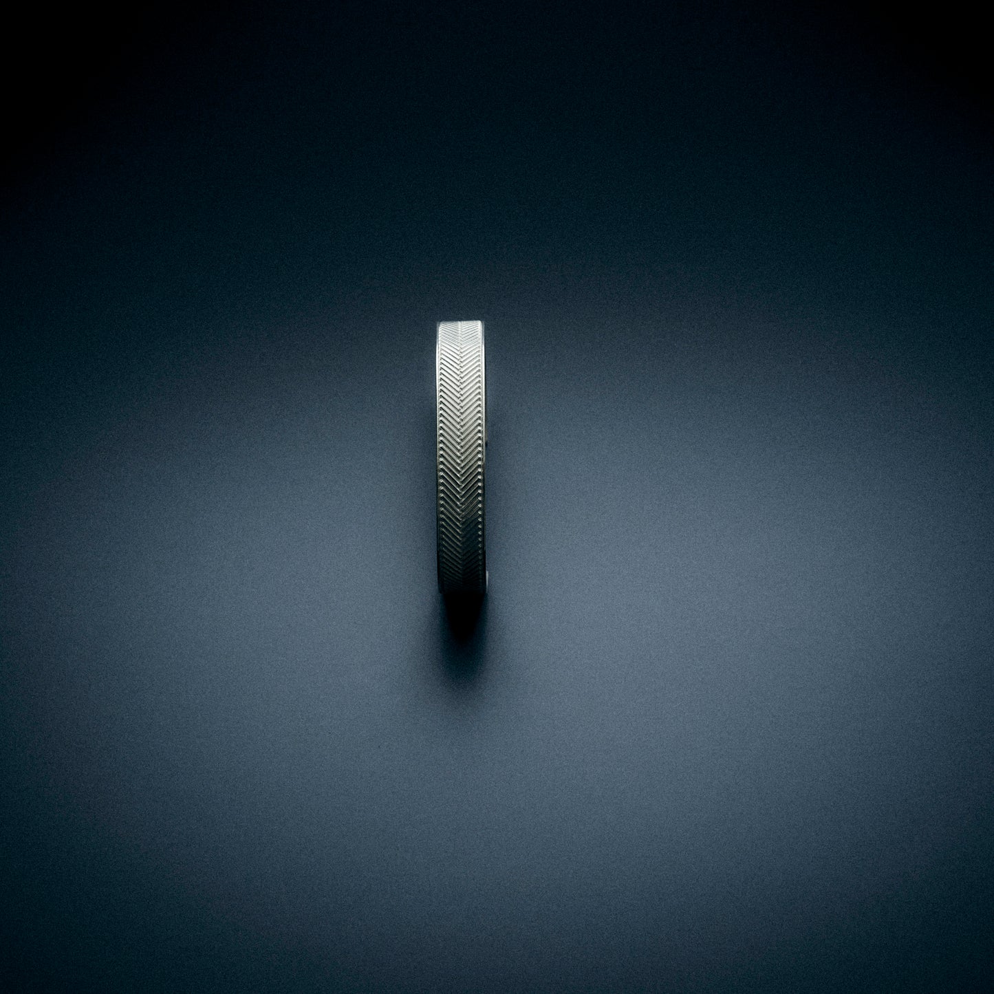 a top view of a silver bracelet with an engraved herringbone pattern